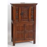 An early 17th century style oak cupboard, carved a crest and linen fold panels, having a door
