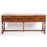 A 17th century style elm dresser base, having four frieze drawers with geometric moulded fronts,