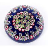 A Paul Ysart glass paperweight, the dark blue ground decorated with multi coloured canes, polished