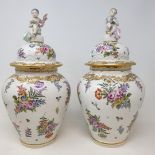 A pair of late 19th century Dresden porcelain vases and covers, each with a Putto surmount to the