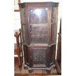 An oak display cabinet, having a glazed door above a panel door, incorporating 17th century