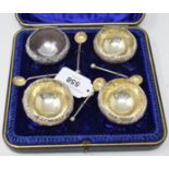 A set of four silver salts, embossed flowers and foliage, on three ball feet, with spoons, Sheffield
