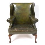 An 18th century style wing armchair, upholstered in green leather, on cabriole legs with pad feet