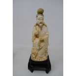 An early 20th century Chinese carved ivory figure, of a man holding a fish, 17.5 cm high, on a