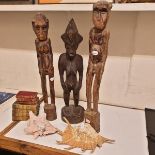An African carved wood figure, 61 cm high, two others similar, assorted shells, and a group of books