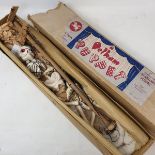 A Pelham puppet, Skeleton, in a brown box Strings tangled.