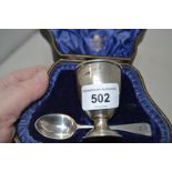 A pair of silver salts, with embossed decoration, with spoons, a silver egg cup and spoon,