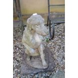 A reconstituted stone figure, of a seated dog, holding a leg up, 68 cm high, mounted on a slab, a