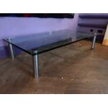 A glass coffee table, on chrome cylindrical legs, probably Marcuso by Marco Zanuso for Zanotta.