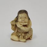 A Japanese ivory netsuke, carved in the form of a boy playing a flute, bare bottomed, signed,
