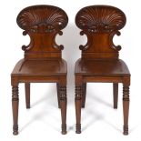 A pair of William IV mahogany hall chairs, with shell carved backs and locus leaf mounted tapering