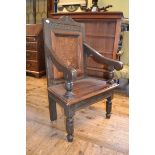 An oak wainscot armchair, the panel back inlaid with a vase of flowers, on turned front legs