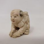 A Japanese carved ivory netsuke, in the form of a child kneeling on a fan, (lacks lacquered signed
