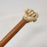 A 19th century malacca cane, the ivory finial carved as a clenched fist, 81 cm long