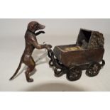 A brass and painted brass dog, pushing a pram, 15 cm wide By RB 2 wheel spokes missing