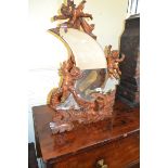 A crescent shape mirror, in a pine frame carved cherubs and a dragon, on a strut leg, 78 cm high