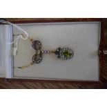 A necklace set with peridot and diamonds in a bow top design