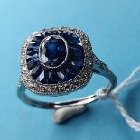 A platinum Art Deco style sapphire and diamond ring. Central oval-shaped sapphire surrounded by a