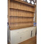 A stripped and painted pine kitchen dresser, the three tier plate rack above a base with three