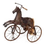 A Continental carved wood galloping horse tricycle, with a leather saddle and stirrups, 90 cm high