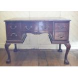 An Edwardian mahogany desk, the leather inset top above an arrangement of five drawers, on scroll