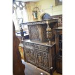 An oak court cupboard, carved in relief 19th century figures in a tavern, shooting and other scenes,