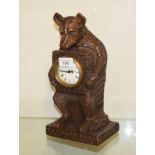 A timepiece, with Arabic numerals, in a Black Forest style carved wood bear case, 30 cm high