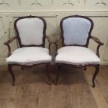 A pair of walnut armchairs, in the French taste, the arms carved scrolling foliage, on cabriole