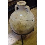 A Roman terracotta amphora, circa 100BC, impressed mark to handle, broken and restored, on a stand