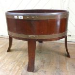 An oval mahogany wine cooler, bound in brass, on splay legs, 74 cm wide