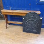 A Gothic style pine bench, 130 cm wide, and an iron fire back, with Royal coat of arms, 56 cm