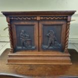 A late 19th century table top oak cabinet, with barley twist columns, the pair of panel doors carved