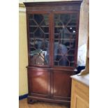 A floor standing mahogany corner cupboard, having a pair of bar glazed doors above a pair of panel