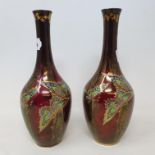 A pair of Devon Fieldings Sylvan Lustrine bottle vases decorated with butterflies on a deep red