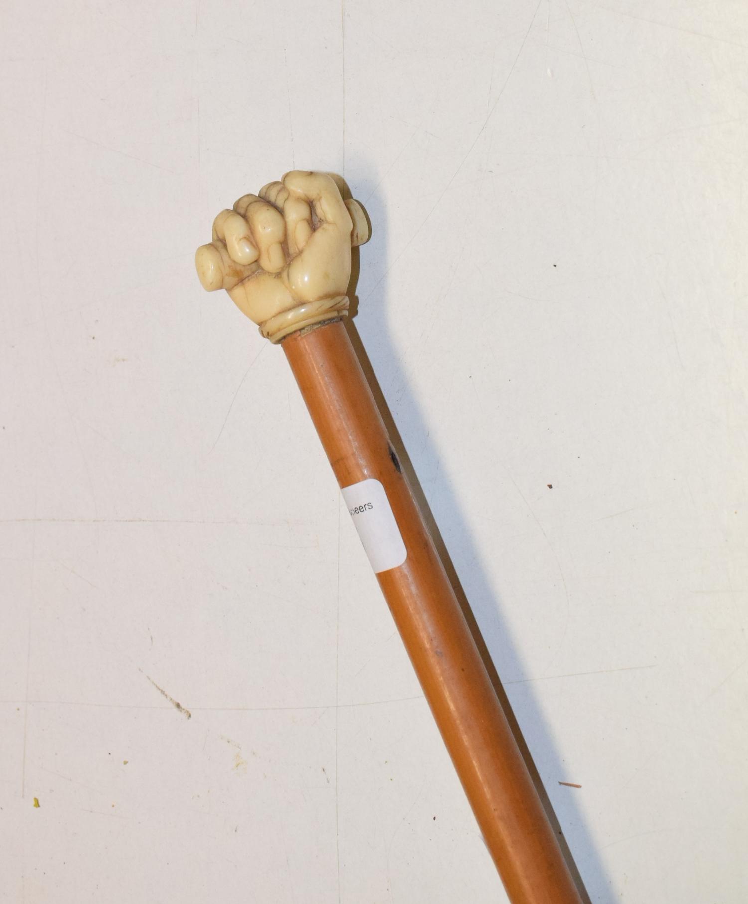 A 19th century mallacca cane, the finial carved as a clenched fist, length 81 cm