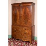 A 19th century bow front mahogany linen press, probably Channel Islands, having a pair of panel