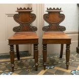 A pair of late Regency mahogany hall chairs, with cartouche shaped backs and tapering reeded front