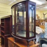 An early 20th century walnut chest, a mahogany bookcase, a mahogany bow front display cabinet, and