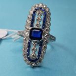 A platinum sapphire and diamond ring, the central cushion shaped sapphire flanked vertically by