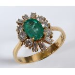 An 18ct gold, emerald and diamond cluster ring, the oval emerald within a surround of twelve