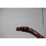 A folk art carved walking stick, with handle in the form of a monkey holding a piece of fruit, 94 cm