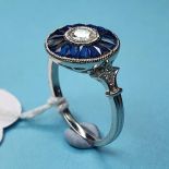 A platinum target-style ring set with a central RBC diamond and a halo of calibre-cut sapphires