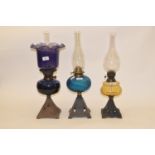 A late 19th/early 20th century spelter oil lamp, with blue glass well, and five others (6)