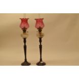 A Piar of early 20th century oil lamps Cranberry glass shades, overall condition good, small chips