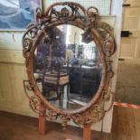A late Victorian oval gilt gesso wall mirror, decorated flowers and foliage, some loss, 134 cm x 102