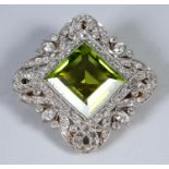 An early 20th century peridot and diamond brooch/pendant, of lozenge form, with peridot set within