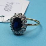An 18ct diamond and sapphire cluster ring, the oval sapphire within a surround of twelve diamonds,