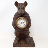 A timepiece, with Arabic numerals, in a Black Forest style carved wood bear case, 30 cm high