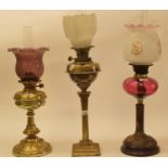 A late 19th/early 20th century brass oil lamp, with cranberry glass shade, and five others (6)