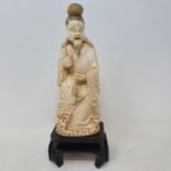 An early 20th century Chinese carved ivory figure, of a man holding a fish, 17.5 cm high, on a